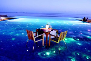 Romantično postavljen sto za večeru sa svećama, koji je odmah pokraj prelepe bistre vode